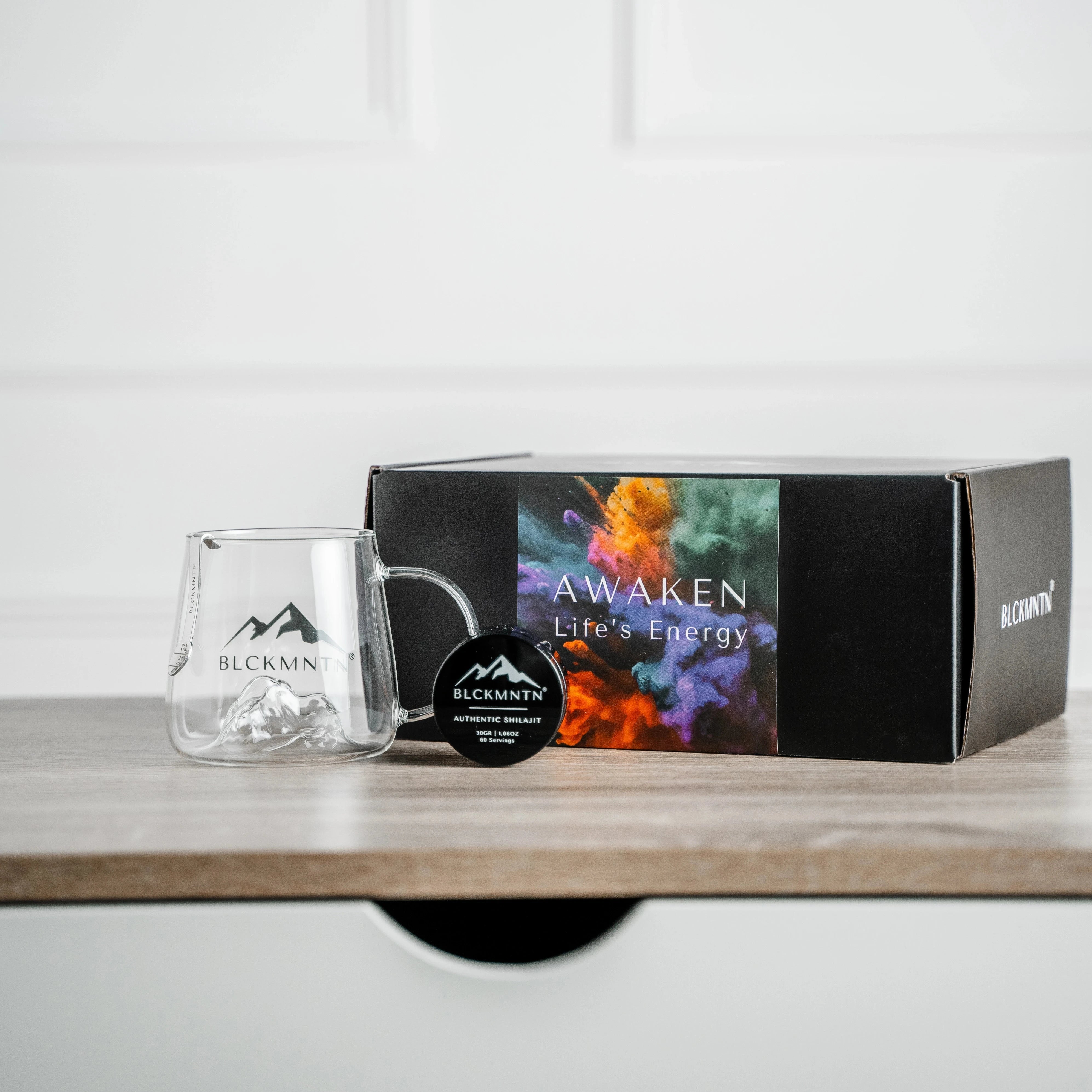 BLCKMNTN Authentic Shilajit met premium doos, exclusief Theeglas en Maatlepel. De pure shilajit resin staat gepositioneerd op een tafel als lifestyle sfeer